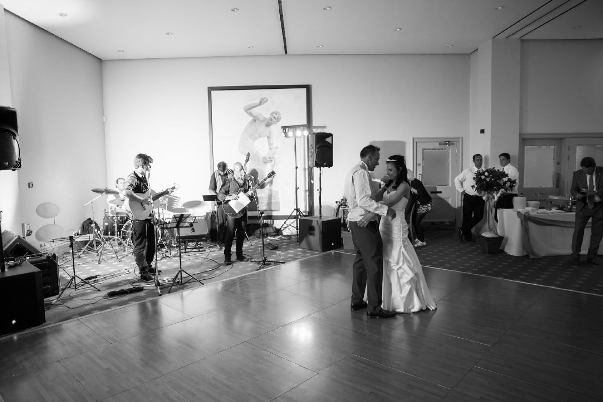 Beccy and Ross dancing on the wooden dancefloor, the band playing at the far end of the room