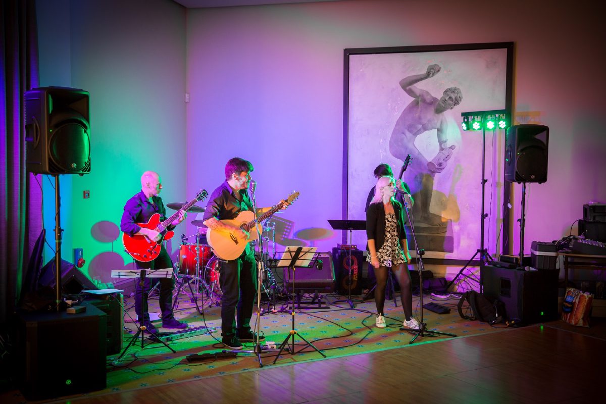 The band lit in green and purple against the end wall of the Wycombe room at Bowood, PA tops on stands either side